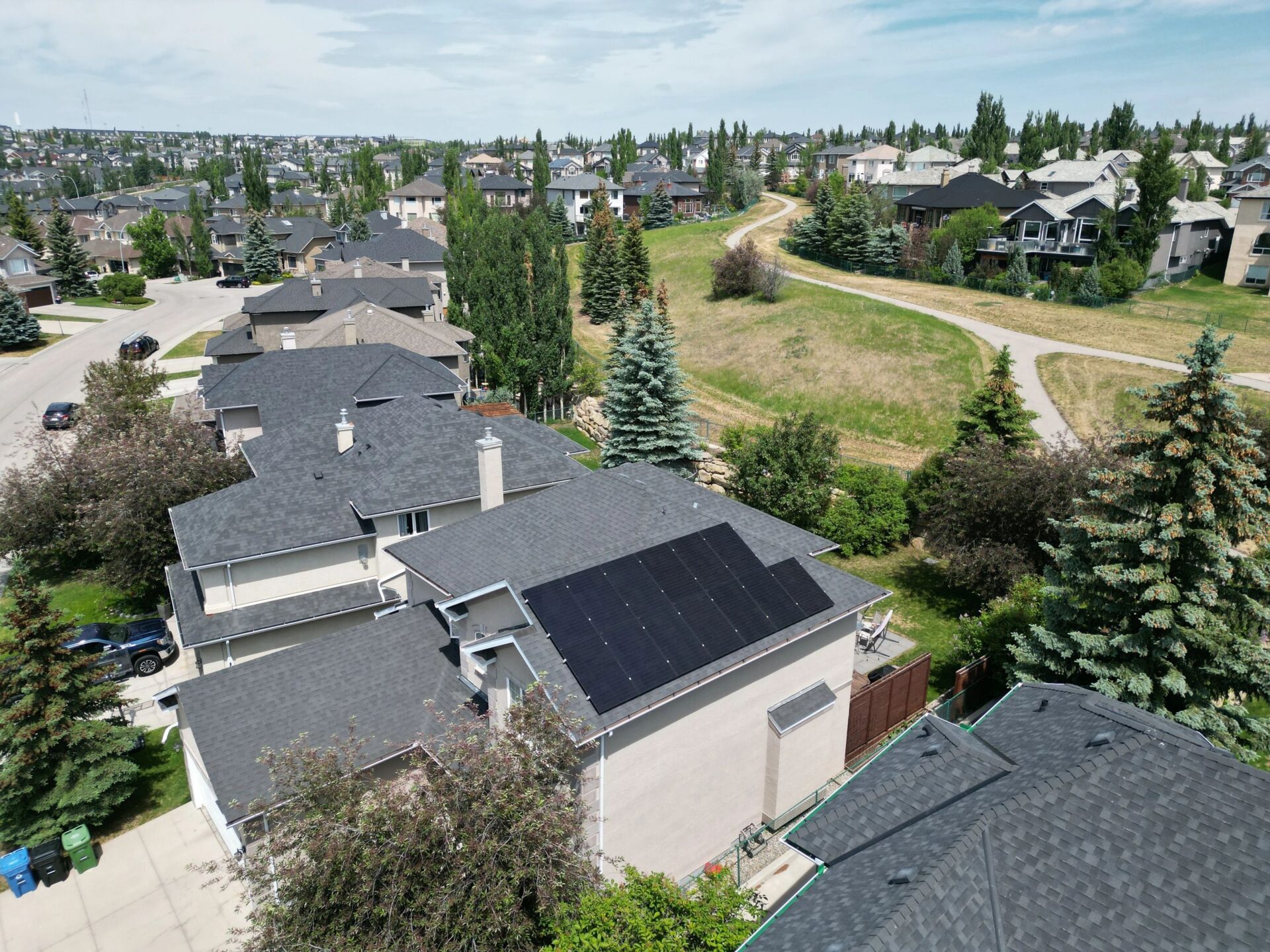 Aerial view of a sleek residential solar panel installation by Calgary solar installers on a dark shingle roof.