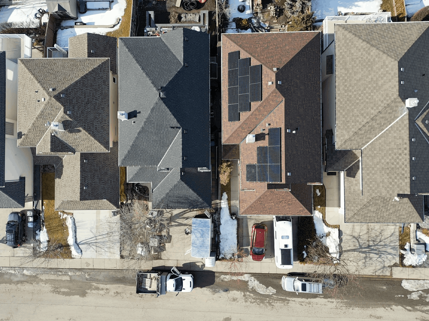 Aerial drone view of a high-efficiency residential solar panel installation on a dark shingled roof in Calgary.