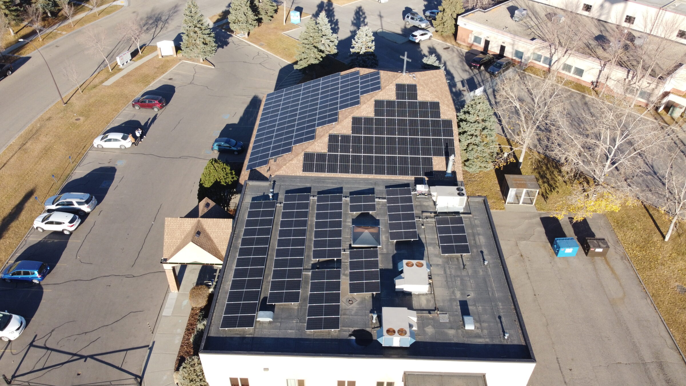 Aerial view of 90 kW commercial solar installation on the ACF church in NW Calgary, featuring mixed sloped and flat roofing systems.
