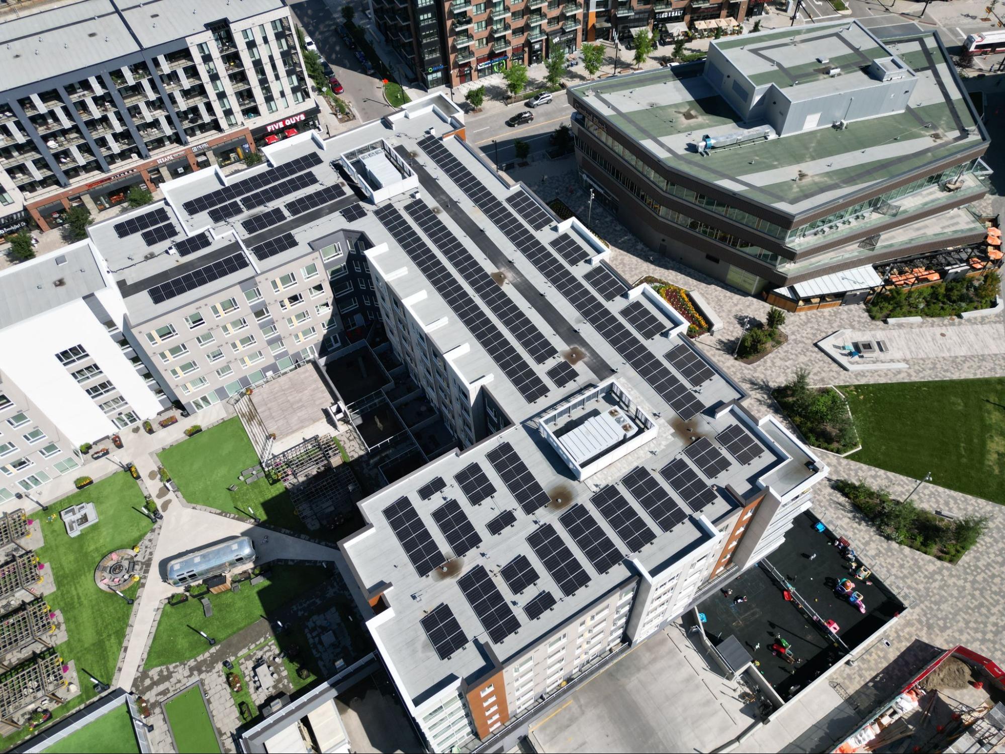An aerial view of a commercial building featuring several rows of rooftop solar panels, illustrating how solar energy is produced by capturing sunlight to power local businesses.