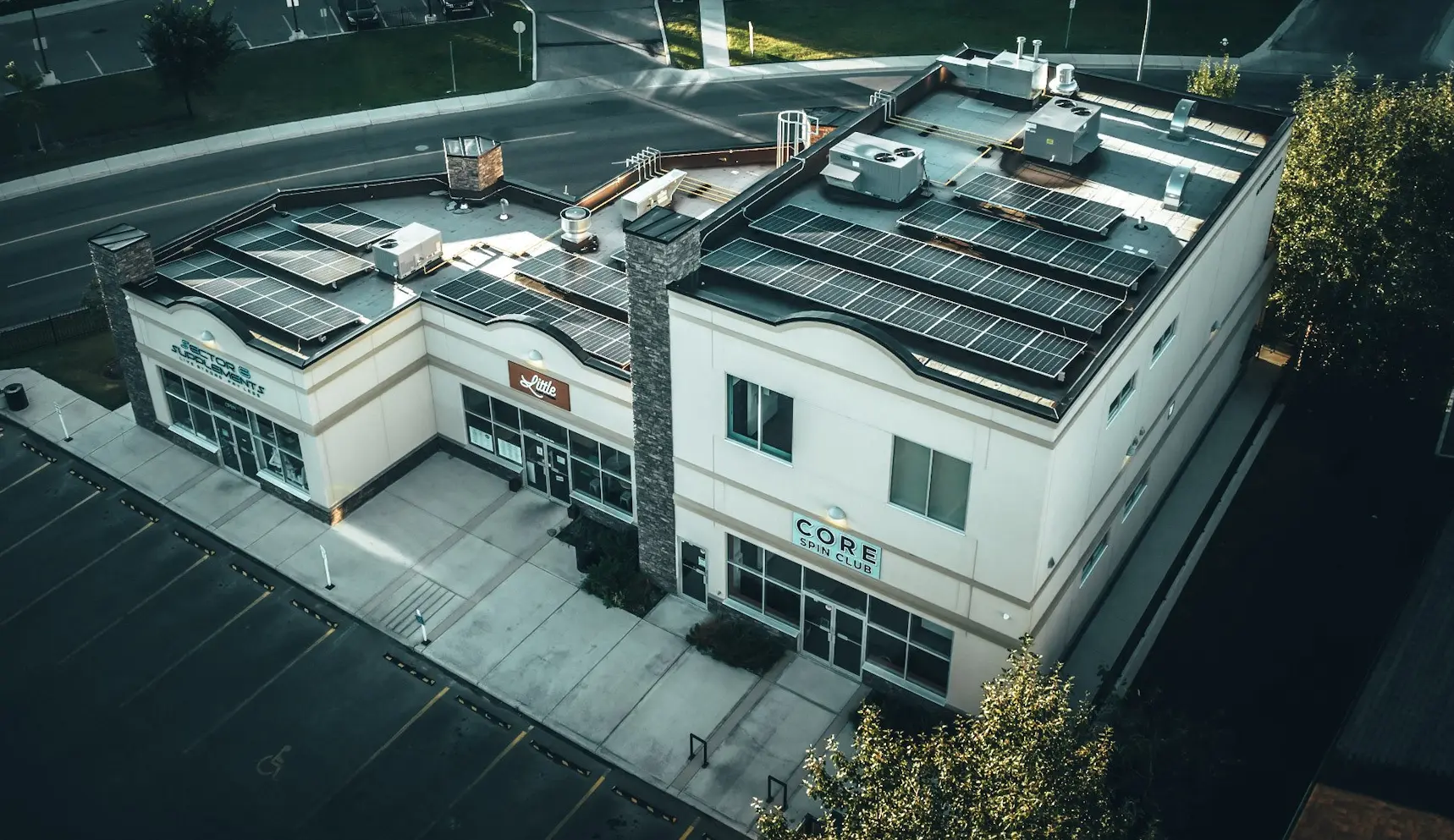 Aerial view of a modern commercial building rooftop with solar panels installed to demonstrate how do solar panels work by converting sunlight into electricity.